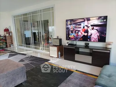 Spacious living room with modern decor and large TV, perfect for family gatherings.