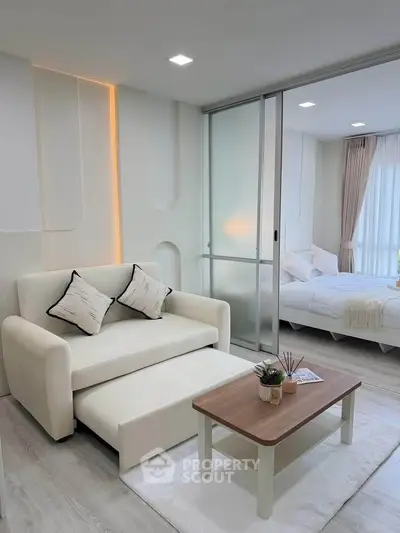 Modern living room with sleek design and cozy bedroom view, featuring stylish furniture and ambient lighting.