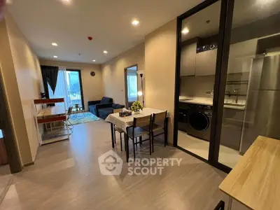 Modern open-plan living room with dining area and kitchen, featuring sleek furniture and natural light.