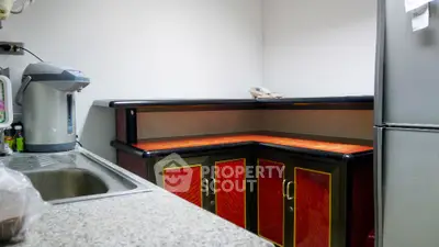 Compact kitchen space featuring red cabinet doors, granite countertop, and modern appliances, ideal for urban living.