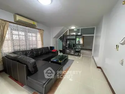 Spacious living room with modern black leather sectional sofa and glass coffee table, perfect for relaxation.