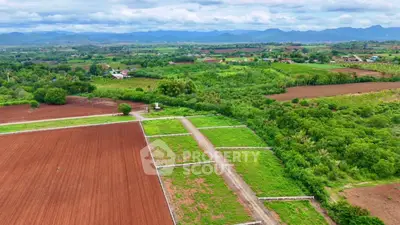 Expansive agricultural land with lush greenery and scenic mountain views, perfect for development or farming.