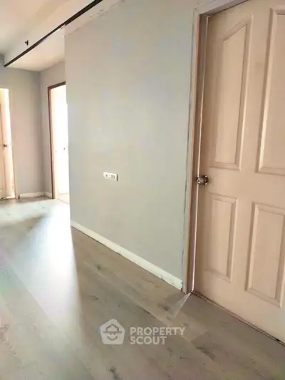Spacious hallway with wooden flooring and modern doors in a contemporary apartment.