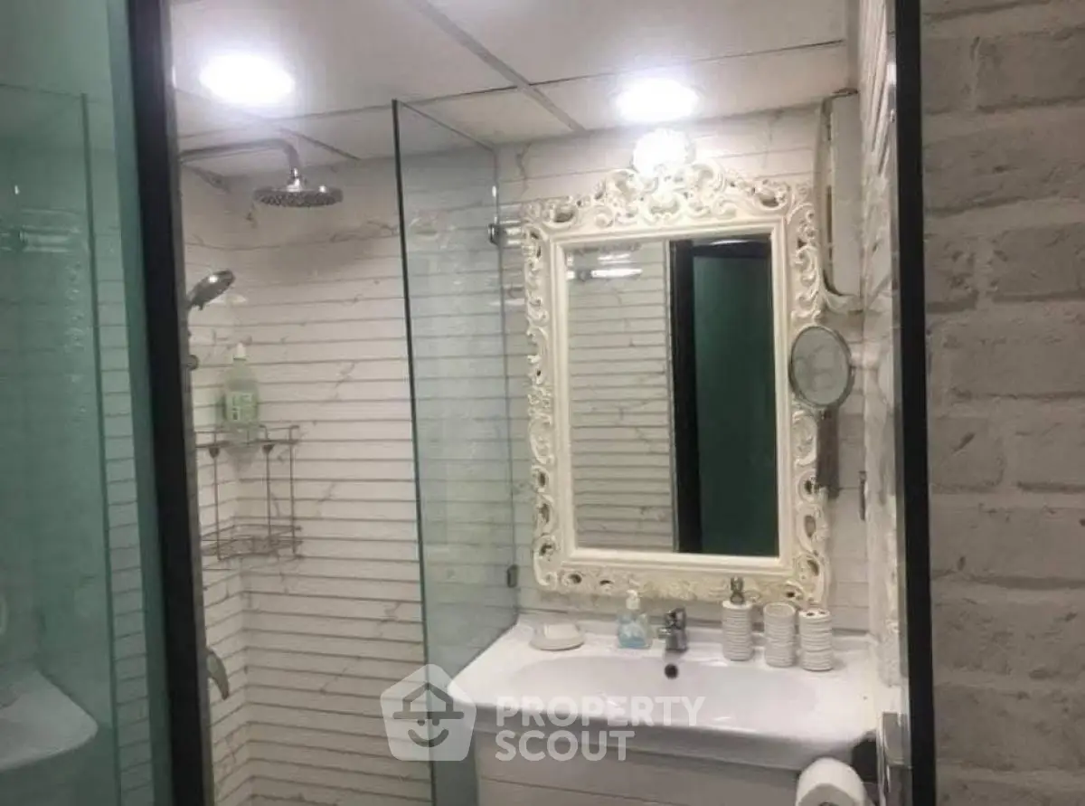 Elegant bathroom with ornate mirror and glass shower enclosure