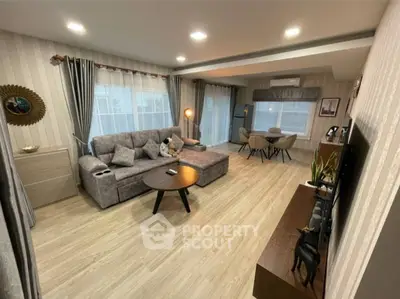Spacious modern living room with stylish decor and dining area, featuring cozy seating and elegant lighting.