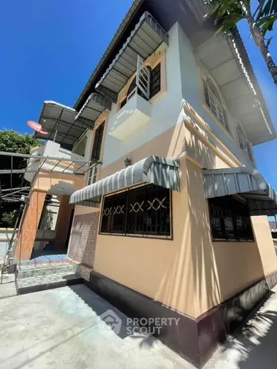 Charming two-story house with unique awnings and vibrant exterior under a clear blue sky.