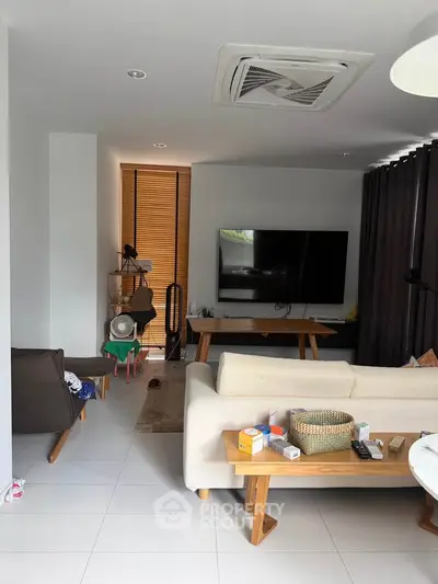 Modern living room with sleek furniture and large TV, perfect for relaxation and entertainment.