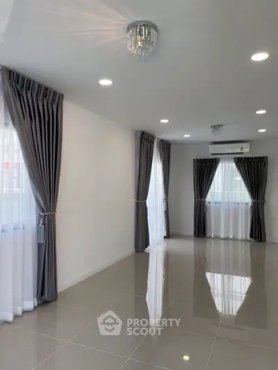 Spacious living room with elegant curtains and modern lighting, perfect for stylish living.