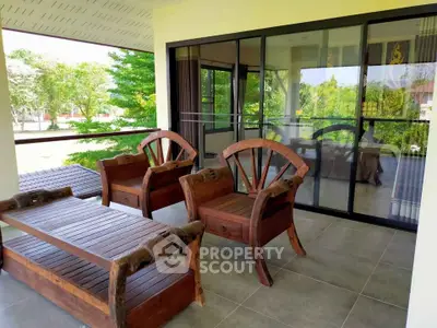 Spacious balcony with stylish wooden furniture and lush garden view, perfect for relaxation.