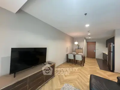 Modern living room with sleek TV setup and stylish dining area in open layout apartment.