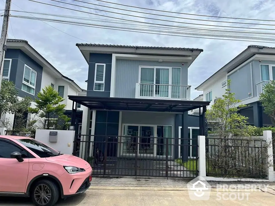 Modern two-story house with sleek design and spacious driveway in suburban neighborhood.