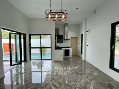 Modern open-plan living area with stylish kitchen and large windows, featuring elegant marble flooring.