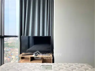 Modern bedroom with city view, featuring a sleek TV and cozy bed setup.