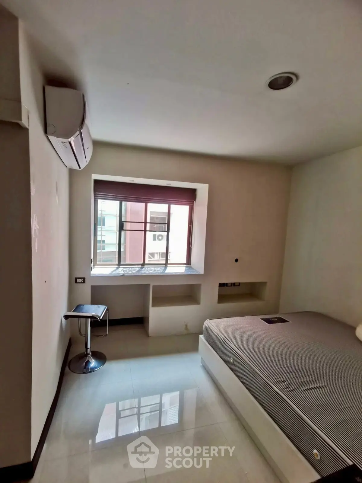 Cozy bedroom with modern design and ample natural light from large window.