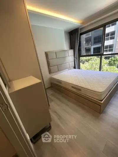 Modern bedroom with large window and stylish headboard in urban apartment
