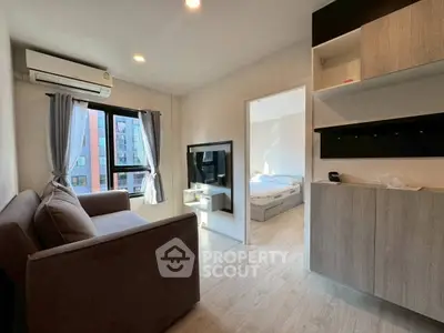 Modern living room with cozy sofa and wall-mounted TV, adjacent to a bright bedroom with large windows.