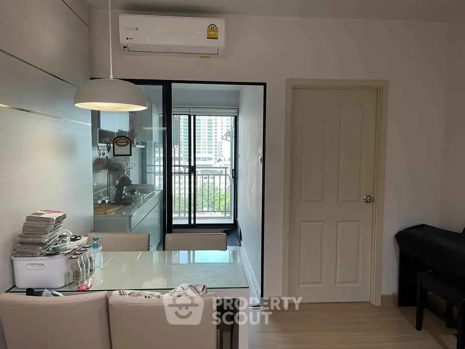 Modern apartment dining area with glass table and kitchen view
