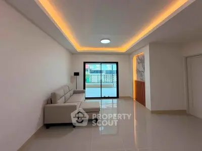 Spacious modern living room with sleek lighting and large window for natural light.