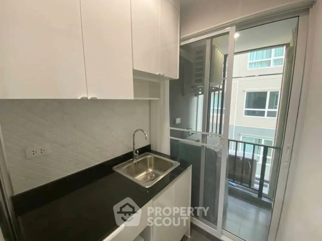 Modern compact kitchen with sleek cabinetry and balcony view