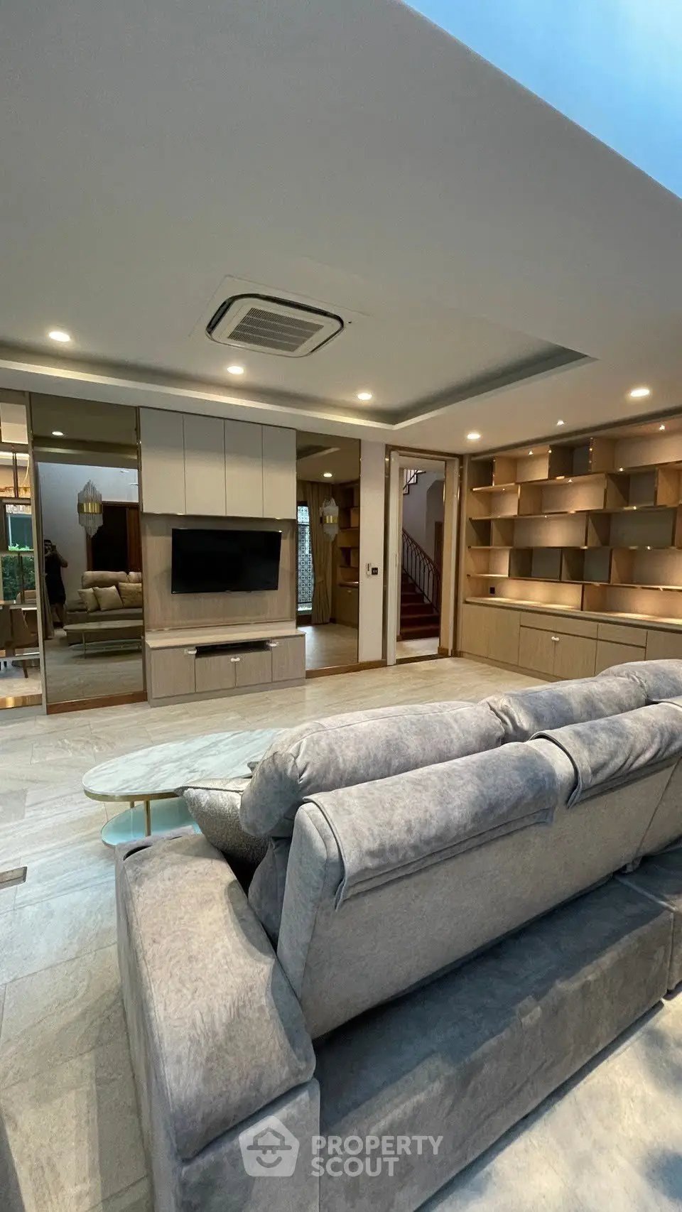 Luxurious modern living room with plush gray sofa and built-in shelving, perfect for relaxation and entertainment.