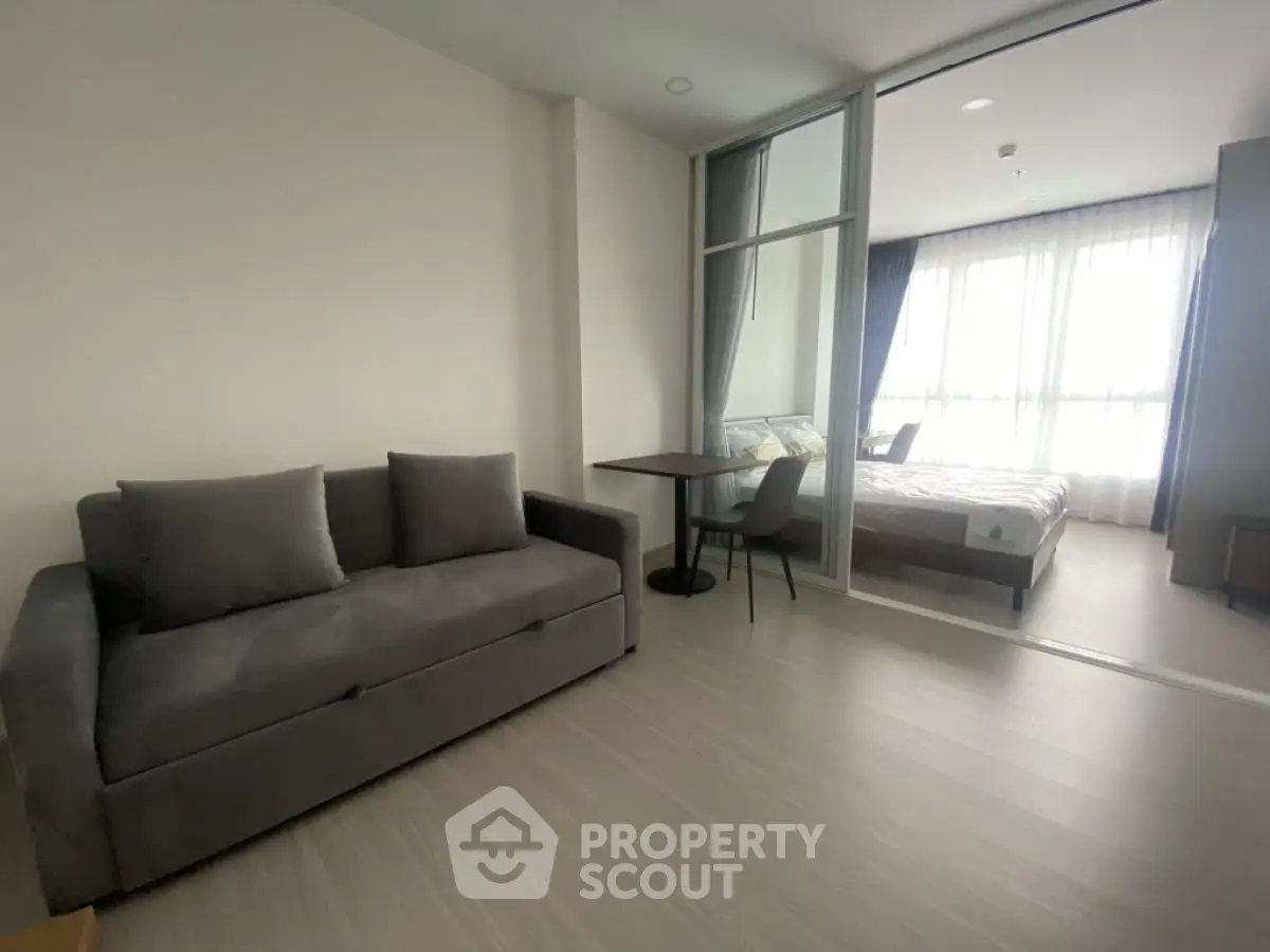 Modern studio apartment with cozy living area and bedroom separated by glass partition.