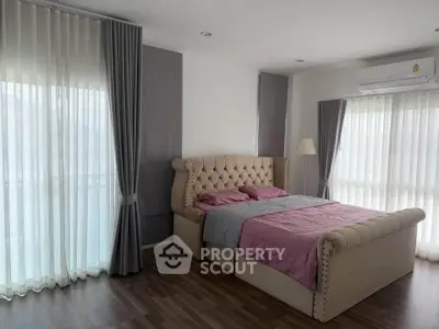 Spacious bedroom with elegant bed and large windows in modern apartment