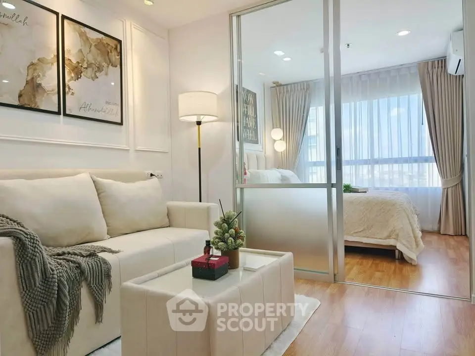Modern apartment with cozy living room and elegant bedroom separated by glass partition.