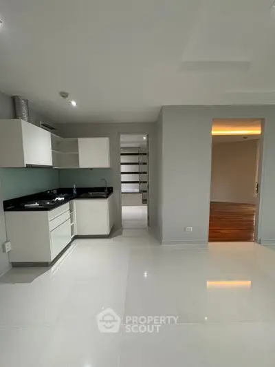 Modern open-plan kitchen with sleek white cabinets and black countertops