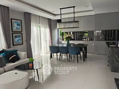 Elegant modern living room with open kitchen, stylish decor, and natural light.