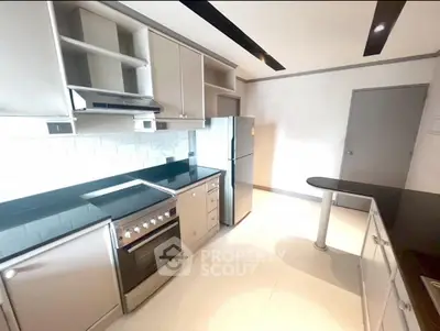 Modern kitchen with sleek appliances and open layout, featuring stainless steel oven and refrigerator.