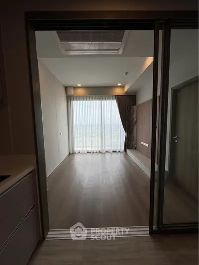 Spacious modern room with floor-to-ceiling windows and elegant wooden flooring.