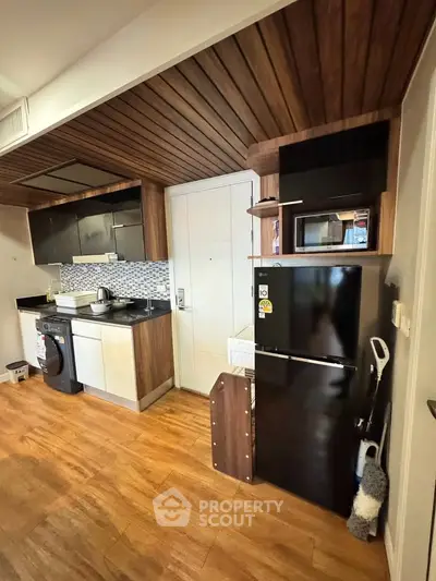 Modern kitchen with sleek appliances and wooden accents, featuring a washing machine and fridge.