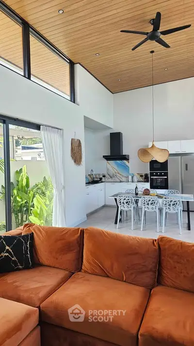 Spacious modern living room with high ceilings, large windows, and stylish kitchen in open layout.