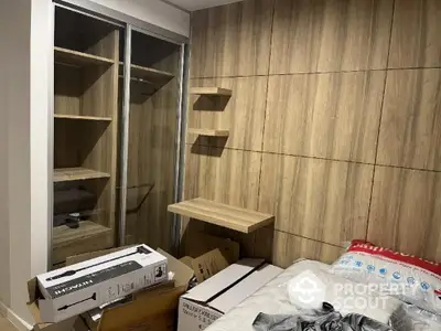 Modern bedroom with wooden paneling and built-in closet, featuring a cozy bed and sleek shelving.