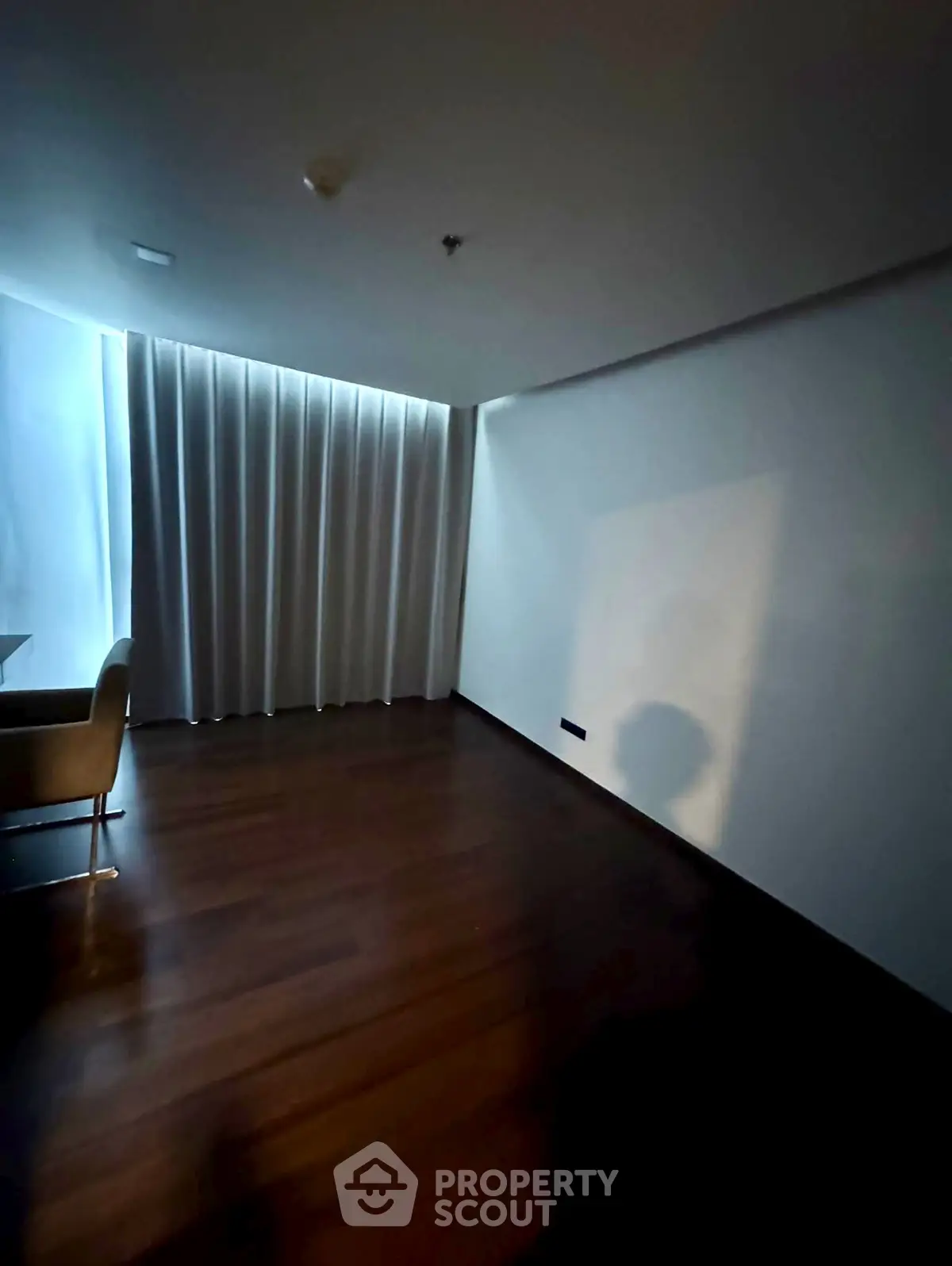 Spacious room with wooden flooring and elegant curtains, ideal for versatile interior design.