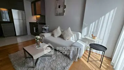 Modern living room with cozy sofa, stylish decor, and open kitchen layout.