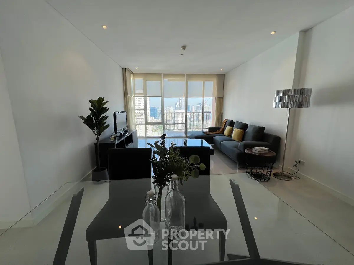 Spacious modern living room with large windows and city view, featuring stylish furniture and elegant decor.
