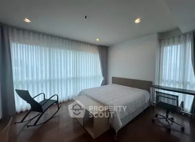 Spacious bedroom with modern furniture and large windows for natural light.