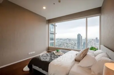 Luxurious bedroom with stunning city view from large window in high-rise apartment.