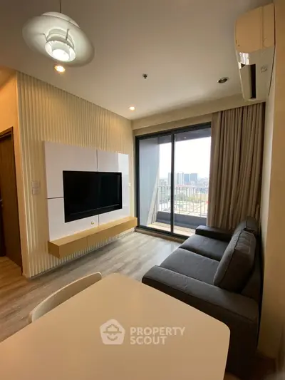 Modern living room with large window and city view, featuring a sleek TV setup and comfortable seating.