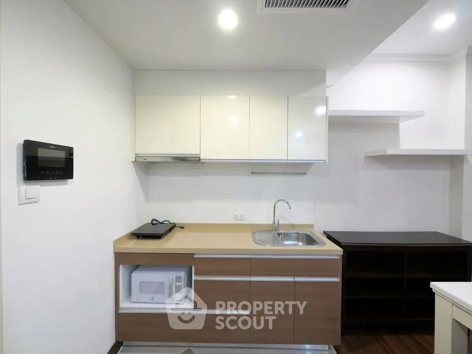 Modern kitchen with sleek cabinetry and built-in microwave in a compact layout.