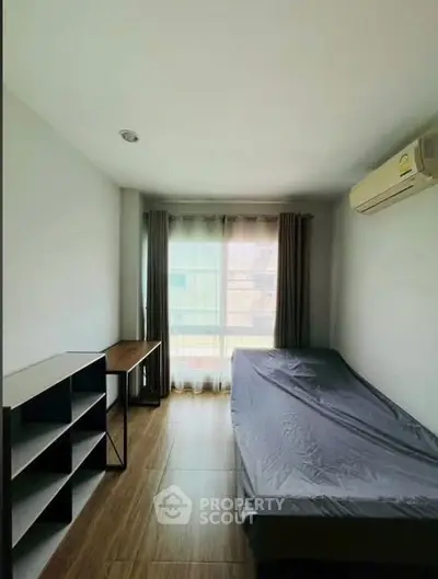 Cozy bedroom with natural light, wooden flooring, and modern furnishings in a stylish apartment.