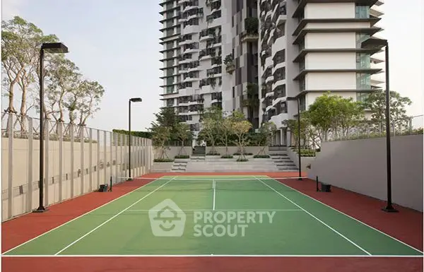 Modern apartment building with tennis court and landscaped surroundings.