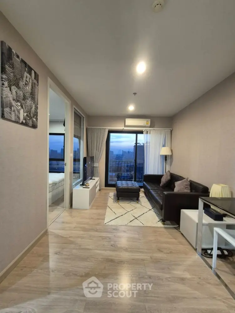 Modern living room with city view, sleek furniture, and wooden flooring in high-rise apartment.