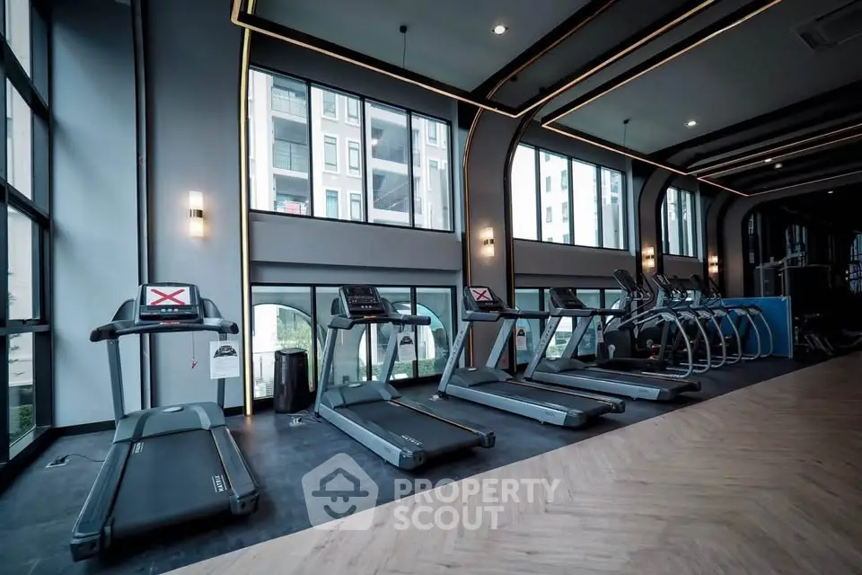 Modern gym with large windows and state-of-the-art equipment in luxury apartment building.