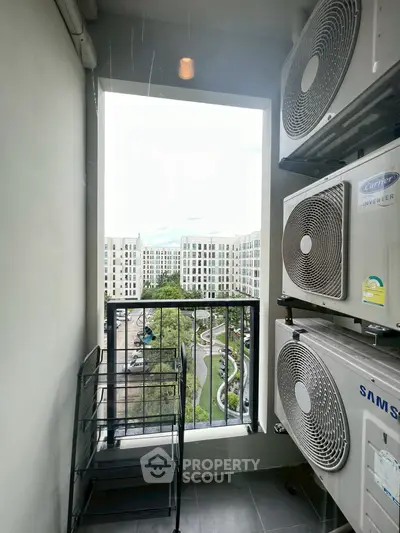 Modern apartment balcony with air conditioning units and scenic view of residential complex.