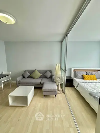 Modern studio apartment with open layout, featuring cozy living area and bedroom separated by glass partition.