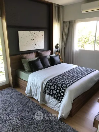 Modern bedroom with stylish decor and large window offering natural light