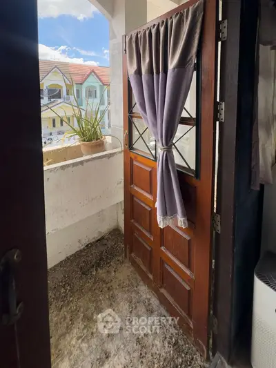Charming balcony view with rustic wooden door and potted plant, perfect for cozy outdoor relaxation.