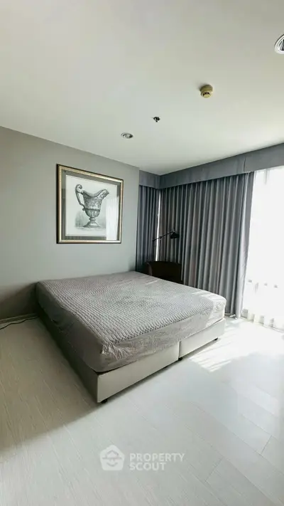 Spacious bedroom with modern decor and large window for natural light.